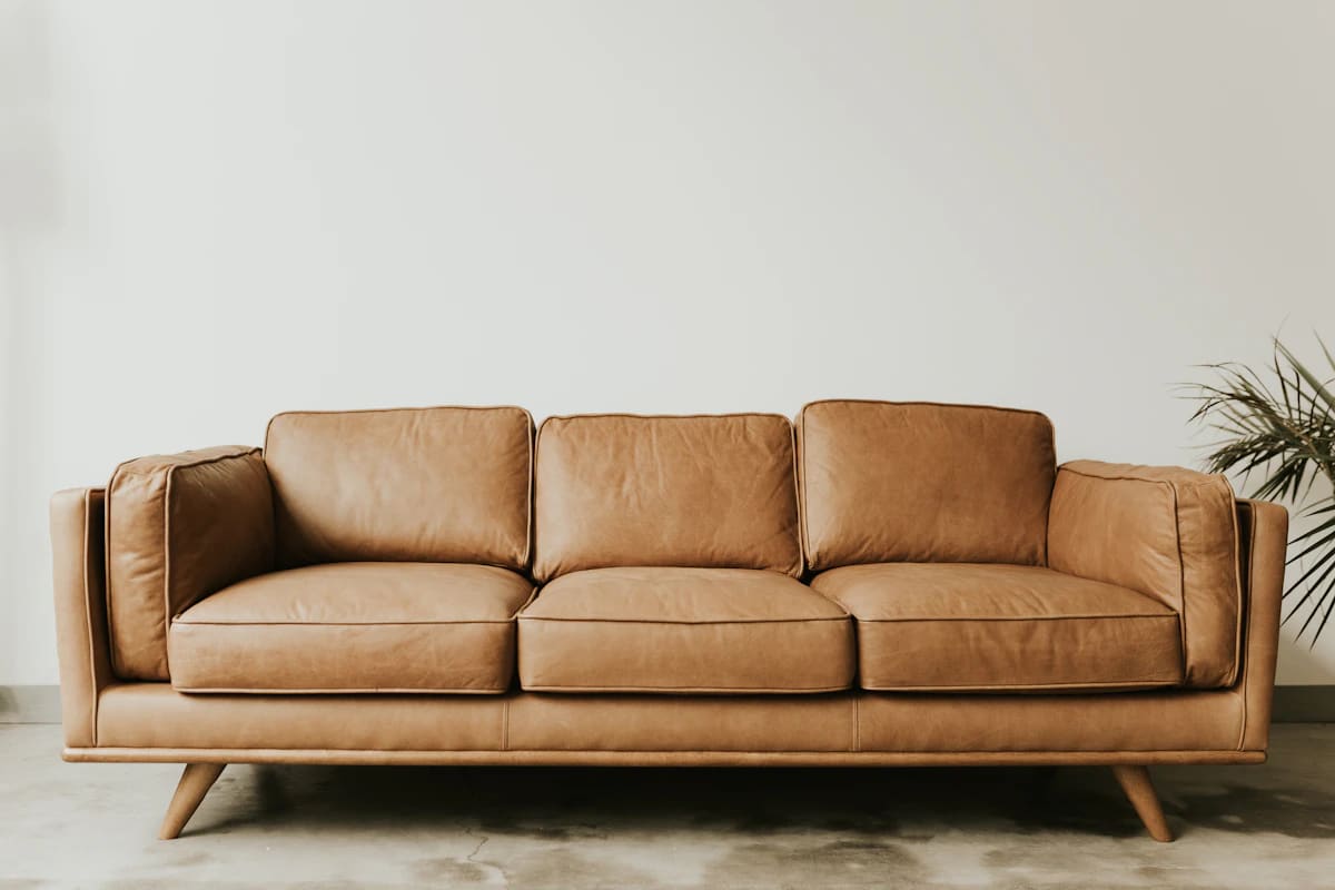 Tan leather three-seat sofa with wooden base